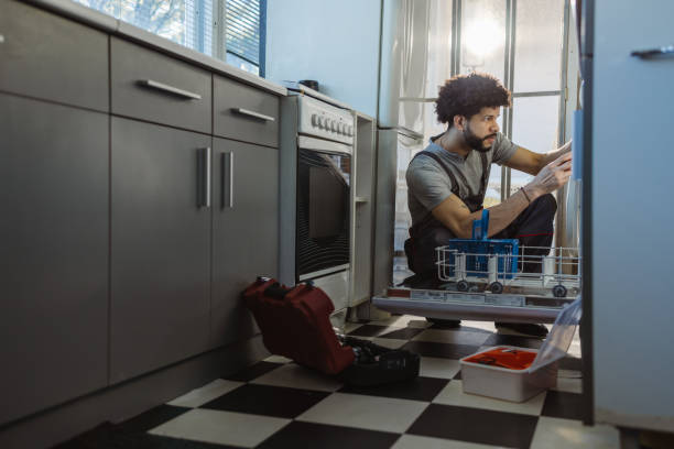 photo of young handyman fixes dishwasher. handyman service photo of young handyman fixes dishwasher. handyman service